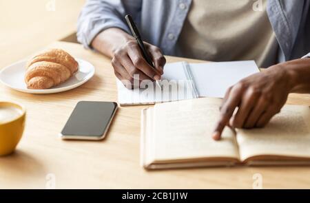 Unrecognizable black guy getting ready for exam in cafe, closeup of hands Stock Photo