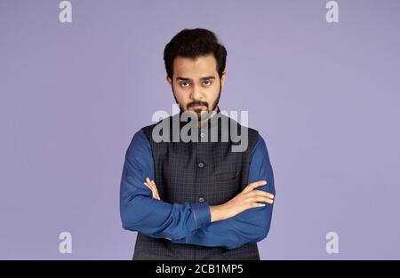 Portrait of serious Indian man with crossed arms on lilac background Stock Photo
