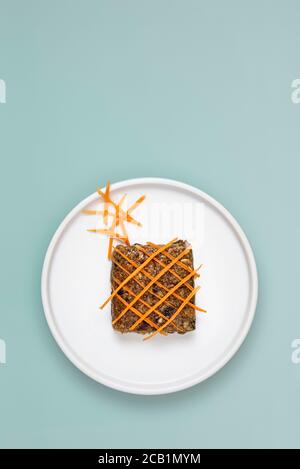 Carrot flapjack topped with fresh grated carrots on pale blue background with copy space Stock Photo