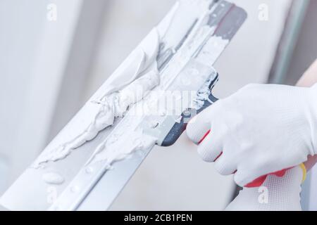 Close View Of Hand Holding Taping Knife With Drywall Compound On And Getting Ready To Patch Walls. Stock Photo