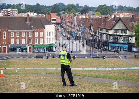 policeman stands guard at cordon at crime scene overlooking English town Stock Photo