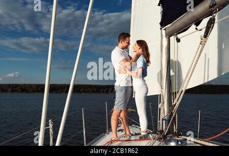 Loving Couple Embracing Standing On Sailboat Sailing On River Outdoor Stock Photo
