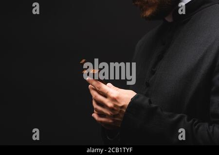 cropped view of priest holding cross isolated on black Stock Photo