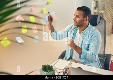 Concentrated bearded male putting stickers on the wall Stock Photo