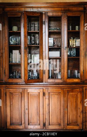 An old wooden cupboard with doors that can be locked with keys and a shallow grate for glass.