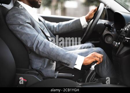 Closeup of black man in suit changing gears in car Stock Photo