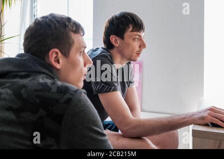 Two young businessmen discuss development strategy while sitting at home. Stock Photo