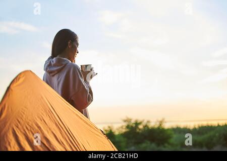 Charming female traveler drinking coffee outdoors in the morning Stock Photo