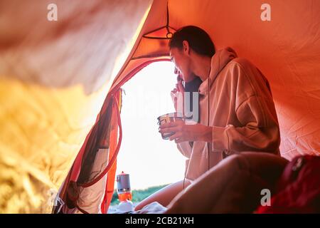 Beautiful young woman having breakfast in camp tent Stock Photo