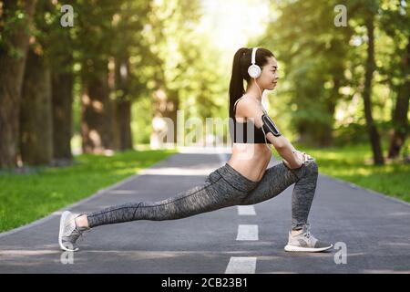 Fit Lifestyle. Sporty Asian Woman Exercising Outdoors In Park, Stretching Leg Muscles