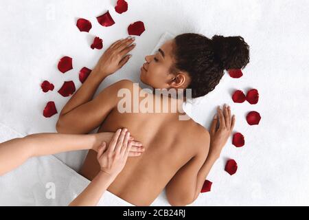 African girl getting healing back massage at spa Stock Photo