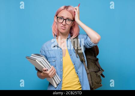puzzled student with books scratching her head trying to make a decision. Stock Photo