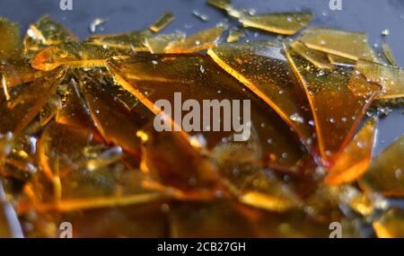 Close-up of amber colored broken glass caramel on grey surface Stock Photo