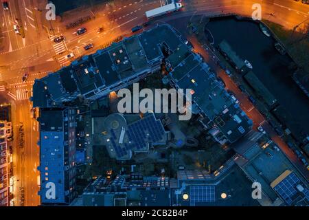 Aerial top view of night european city with buildings roofs and illuminated roads with cars.