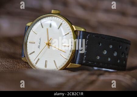 Vintage russian Raketa wristwatch of the 1960s with golden hands and white dial on a brown leather surface Stock Photo