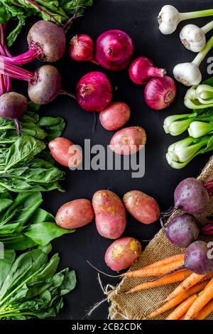 Carrot, potato, beet, onion and spinach on black background top view Stock Photo