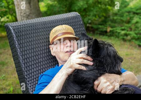 Outdoor portrait of a senior man sitting with his dog in a garden Stock Photo