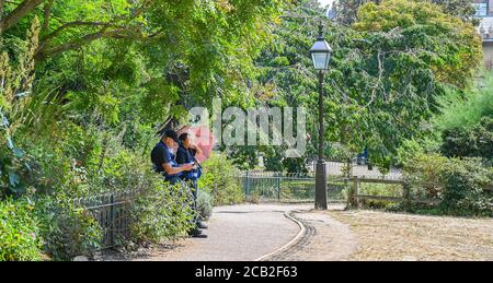 Brighton UK 10th August 2020 - Security staff find some shade in Pavilion Gardens Brighton on a hot sunny day as temperatures again reach into the 30s in parts of the South East : Credit Simon Dack / Alamy Live News Stock Photo