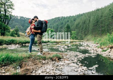 Young couple nature explorers kissing by the river in the mountains Stock Photo