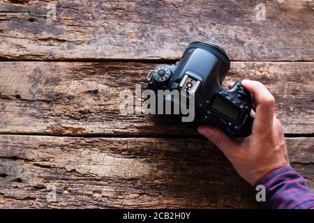 photographer holds a camera on a wooden background with space for text Stock Photo