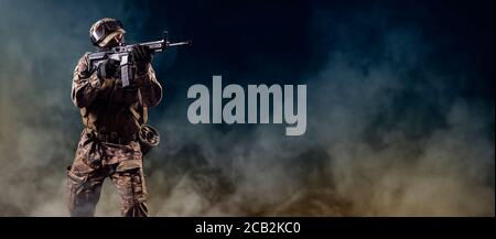Soldier of special forces aiming on target.  Infantryman fighting with terrorism. Commando on smoky background with rifle. Stock Photo