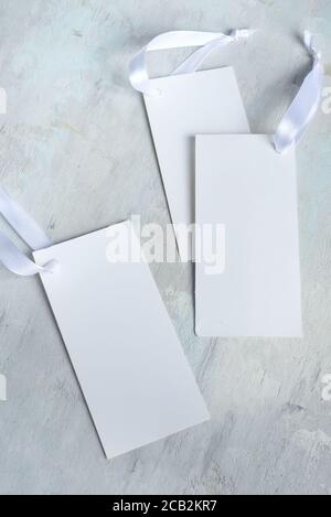 Blank mock-up white empty greeting or invitation cards with ribbons on a light grey concrete background, copy space. Top view. Congratulation card. Stock Photo
