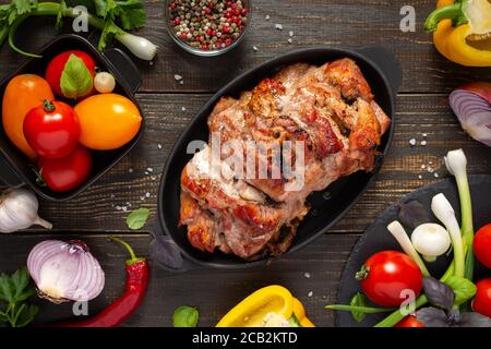 Baked pork ham on a wooden background, fried piece of meat with spices, fresh vegetables, top view Stock Photo