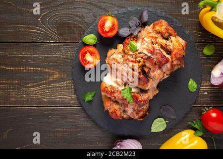 Baked pork ham on a wooden background, fried piece of meat with spices, fresh vegetables, top view Stock Photo