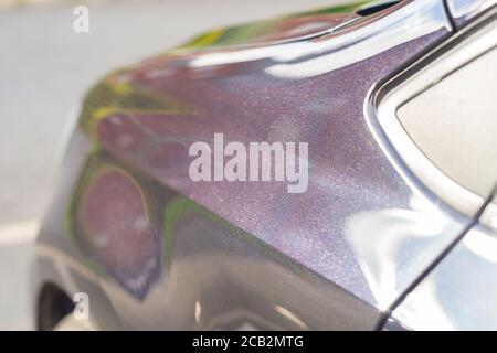 Freshly polished and waxed bodywork of a car with black pearlescent paint. It appears black from a distance but has a sparkly purple lustre up close. Stock Photo