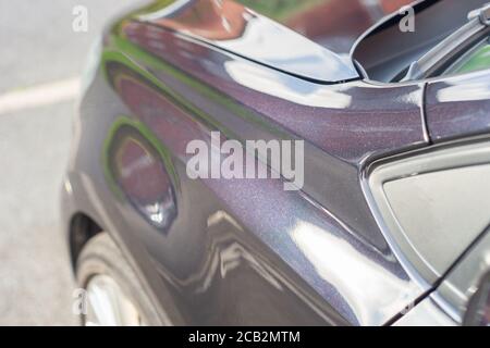 Freshly polished and waxed bodywork of a car with black pearlescent paint. It appears black from a distance but has a sparkly purple lustre up close. Stock Photo