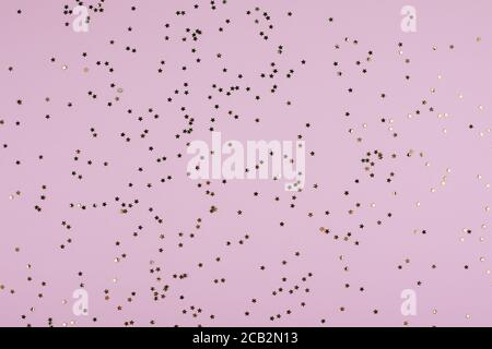 Golden sparkles stars on pink pastel trendy background. Festive background. Flat lay, top view. Stock Photo