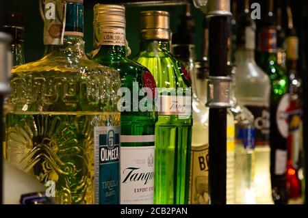 Several colored alcohol bottles displayed on a shelf in a pub Stock Photo
