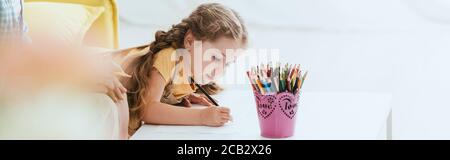 cropped view of nanny near adorable child drawing with pencil, horizontal image Stock Photo