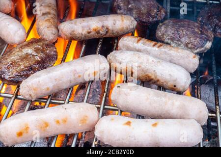 Sausage and beef burgers cooking on a barbecue. Stock Photo