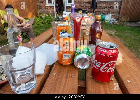 Empty drinks cans and bottles on a garden table in the summer. Stock Photo