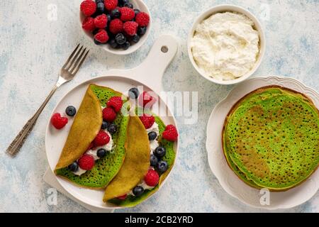 Spinach crepes with cheese , raspberries and blueberries. Stock Photo