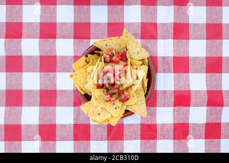 Plate of nachos viewed from above on a red and white checkered tablecloth. Stock Photo