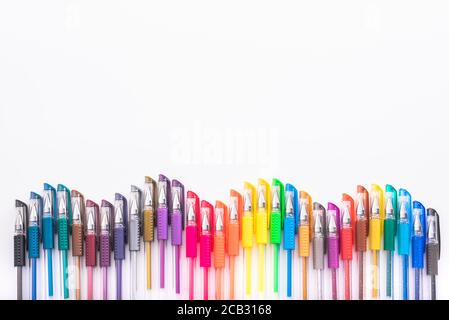 Group of colorful pens for drawing, arranged in a waveform on a table isolated on white. Stock Photo