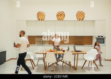 European family in white kitchen interior minimalism. Mother cooking dinner, child playing. Home, family concept Stock Photo