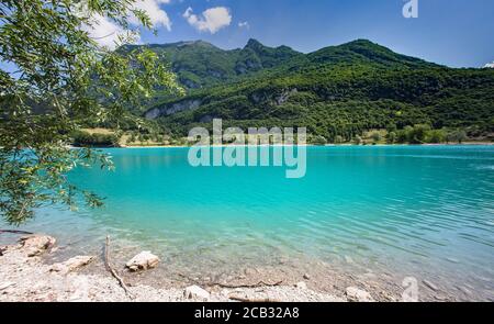 Sunny Panorama of Lake Tenno surrounded by Italian mountains Stock Photo