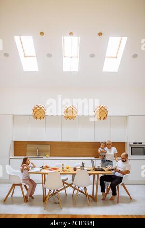 Using laptop at home. Chindren and parents in kitchen busy with cooking, online working. Family, home, love concept Stock Photo
