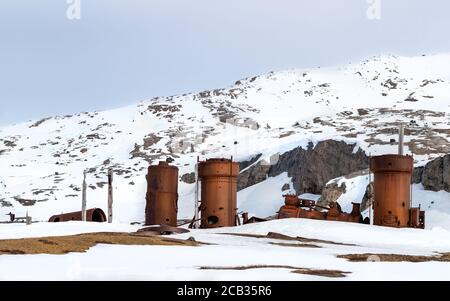 Abandoned marble mining machinery at Camp Mansfield, New London, Svalbard. Snow covered mountain background with blue sky. Stock Photo