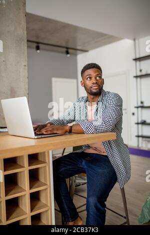 Education, home, people and technology concept-young african male student having on-line classes at home, working on laptop Stock Photo