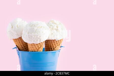 Ice cream cones in a blue bucket on a pink background. A wafer-style ice cream cone.  Stock Photo