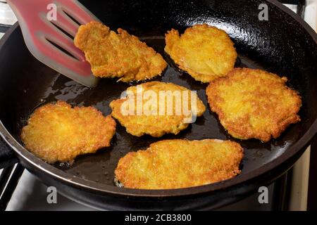 The cooking process in a pan of potato pancakes. Frying potato pancakes in vegetable oil. Stock Photo