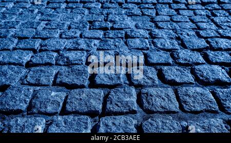 Black cobbled stone road background. Black or dark grey stone pavement texture. Ancient paving stone background Stock Photo