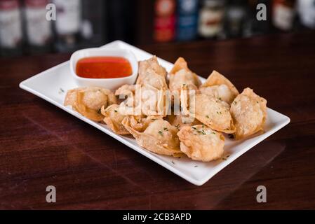 Selective focus shot of crispy fried wontons with a sauce on a wooden table Stock Photo