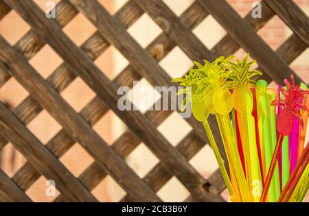 Decoration in form a pineapple and cocktail tubes on a wooden lattice background. Stock Photo
