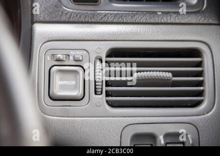 Close-up of a gray plastic panel with buttons and a toggle switch for automatic adjustment of side mirrors with white symbols under the air conditioni Stock Photo