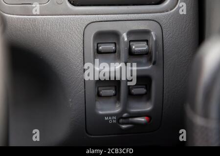 Buttons for controlling windows with opening and closing and electric drives and locks for black doors with plastic upholstery in a modern car located Stock Photo